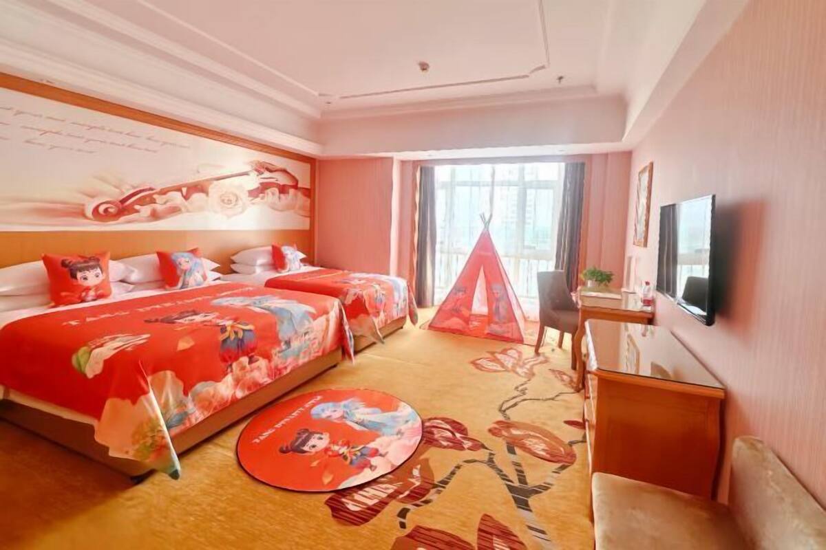 Une chambre d’hôtel avec un lit, un bureau, une chaise, une télévision et une fenêtre.