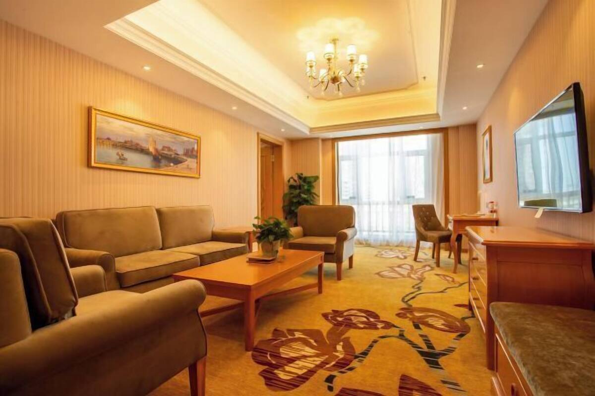 Une chambre d’hôtel équipée d’un canapé, d’une table basse, d’un téléviseur et d’une grande fenêtre.