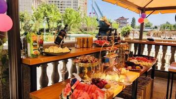A buffet table with various food items and a view of a traditional building in the background.