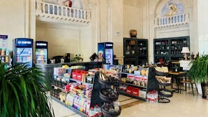 A hotel lobby with a reception desk, self-service beverage machines, and a variety of packaged goods on shelves. - Vienna International Hotel (Khorgos Port) (Khorgas)