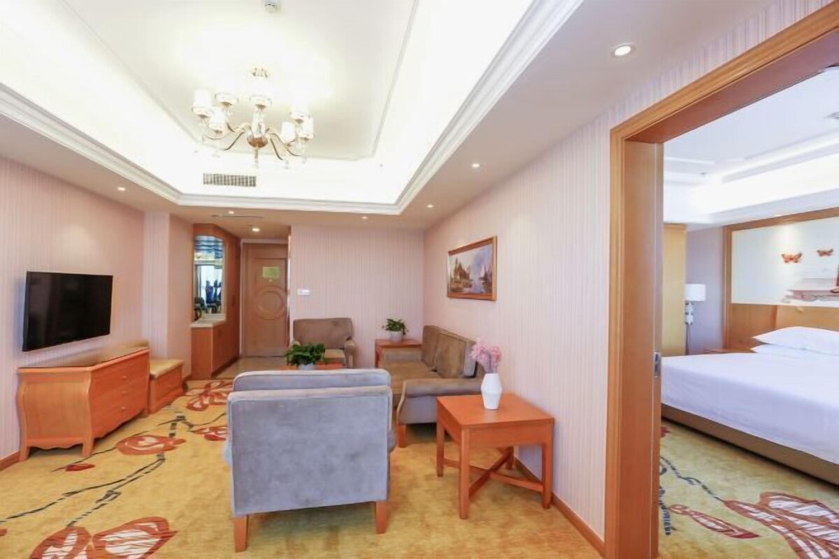 Ein Hotelzimmer mit einem Bett, einem Fernseher, einem Sofa, einem kleinen Tisch und einem Sessel.