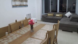 A dining area with a long table and chairs, a sofa, and a painting on the wall. - Heart of Jerusalem 4 rooms - modern - WIFI (Jerusalem)