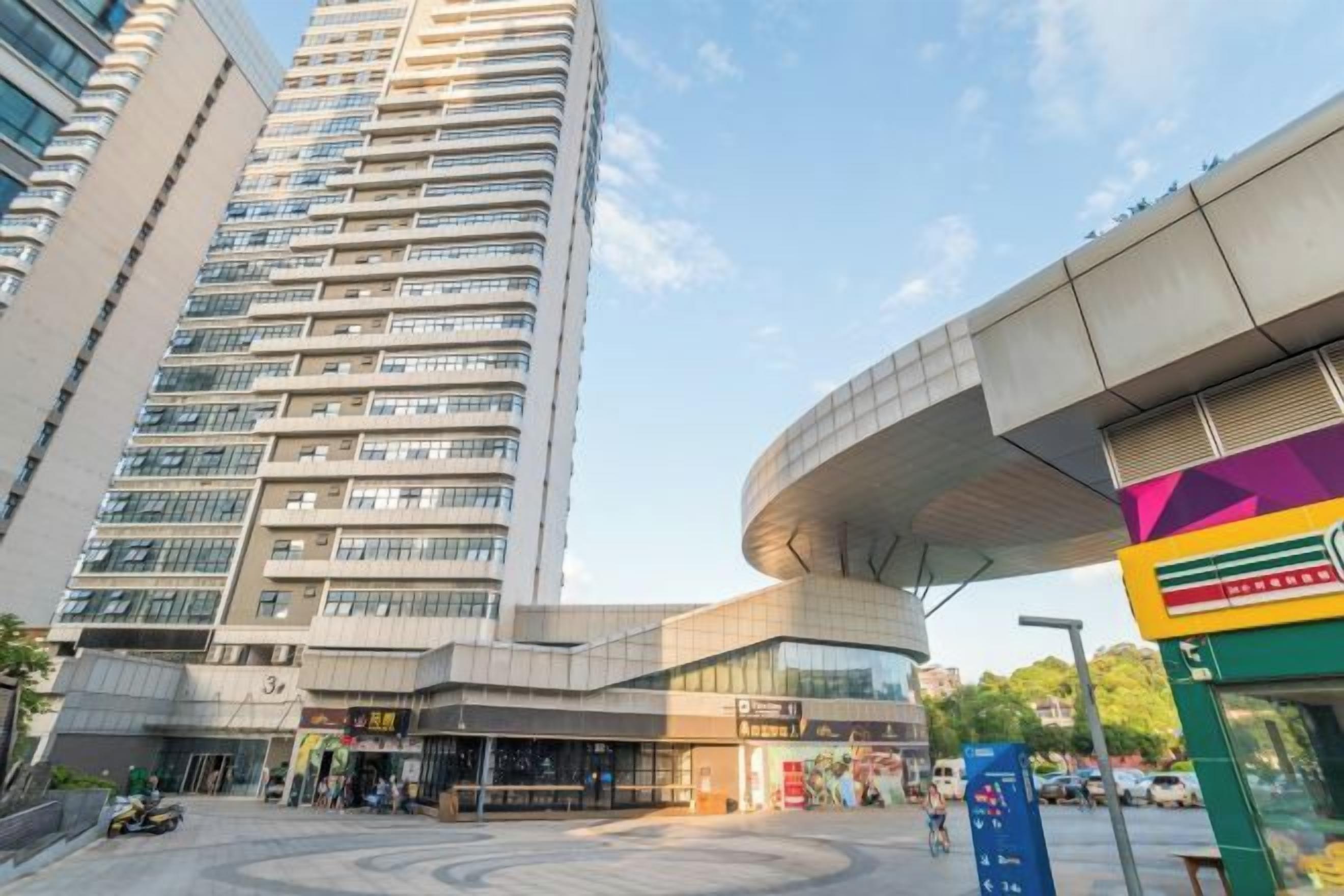 A modern building with a curved glass facade and a flat-roofed structure.