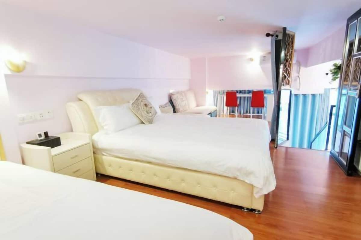 A bedroom with a large bed, a bedside table, and a window with curtains.