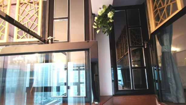 Een modern interieur met glazen balustrade, houten vloer en een decoratieve plant.
