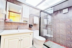 Ein modernes Badezimmer mit Duschkabine aus Glas, einem weißen Waschbecken und einer Toilette.