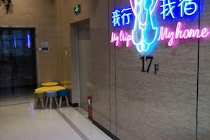 Interior de un hotel con un letrero de neón que dice 'Mi hogar' y el número de habitación '17F'.