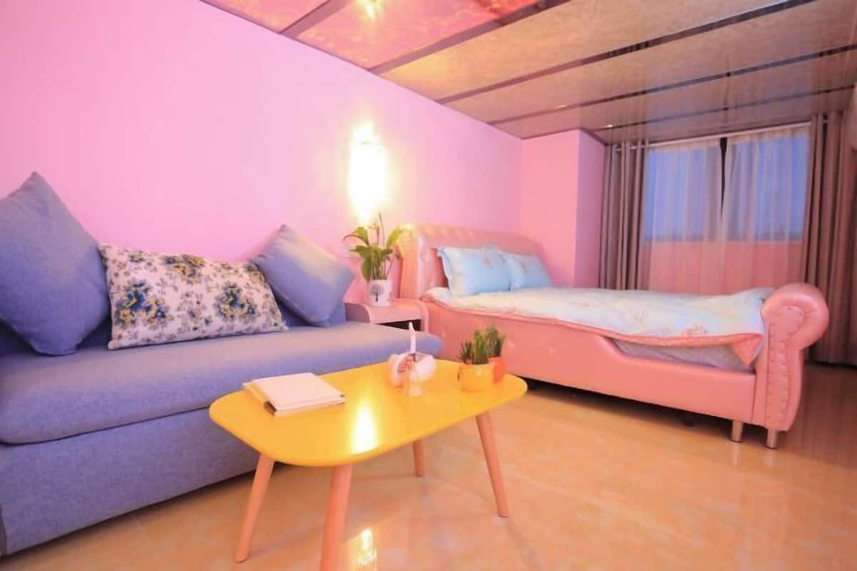 A cozy room with a sofa, a small table, and a bed.