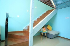 Ein modernes Interieur mit einer Holztreppe, einer kleinen Sitzecke mit Kissen und einer Glasdecke.