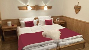Un lit bien fait, avec une literie blanche et rouge, deux tables de chevet avec des lampes et une tête de lit en bois.