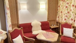 Une pièce chaleureuse avec un canapé rouge, une petite table avec un verre et des meubles en bois.