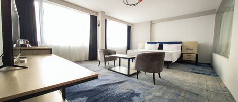 A hotel room with a bed, a desk, a chair, a TV, and a large window.