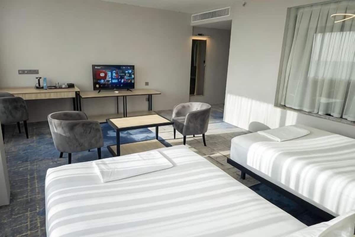 Habitación de hotel con dos camas, un escritorio con televisor y dos sillas.