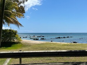 Uma praia com céu claro, areal arenoso e alguns barcos.