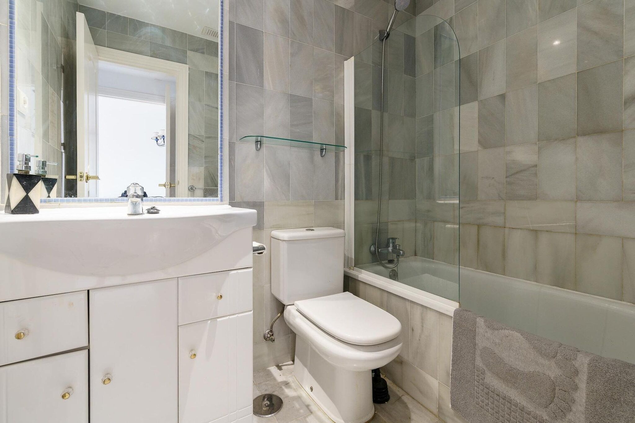 A modern bathroom with a glass shower enclosure, a white toilet, and a sink with a mirror above it.