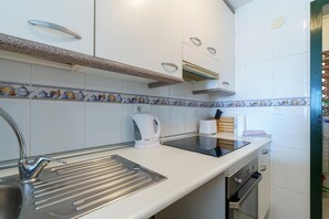 Een moderne keuken met witte kasten, een roestvrijstalen spoelbak, een koffiezetapparaat en een inbouwoven.