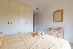 A bedroom with a bed, a dresser, a mirror, and a wardrobe.