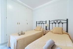 Een slaapkamer met twee eenpersoonsbedden, een garderobe en een nachtkastje met een lamp.