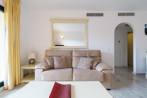 A living room with a sofa, a table, a lamp, and a mirror.