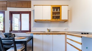 A compact kitchen with white cabinets, a wooden countertop, and a dining area with a table and chairs. - Apartment in preferred in Cala de Mijas (Mijas)