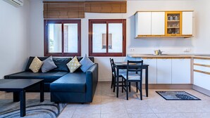 A living room with a sofa, a dining table, and chairs. There is a kitchen area with cabinets and a window. - Apartment in preferred in Cala de Mijas (Mijas)