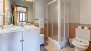 A bathroom with a shower enclosure, a sink with a mirror, and a toilet. - Apartment in preferred in Cala de Mijas (Mijas)