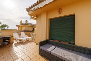A patio with outdoor seating, a table, and a green shutter door. - Apartment in Mijas with pool (Mijas)