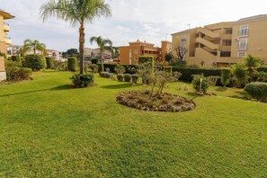 A well-maintained garden with a circular flower bed, surrounded by neatly trimmed hedges and a variety of shrubs. - Apartment in Mijas with pool (Mijas)