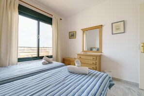 A hotel room with a bed, a dresser, a mirror, and a window with curtains. - Apartment in Mijas with pool (Mijas)