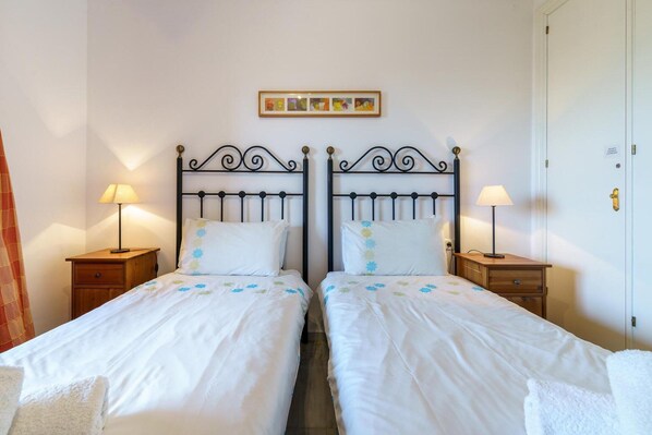 A double bed with a metal frame, two bedside tables with lamps, and a wall-mounted picture above the bed.