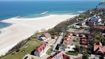 Vista aerea di una zona residenziale costiera con case, una spiaggia e un molo.