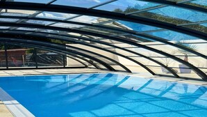 An indoor swimming pool with a glass ceiling, clear blue water, and a view of the surrounding area. - Comfortable, convenient apartment, pool included (Jaroslawiec)