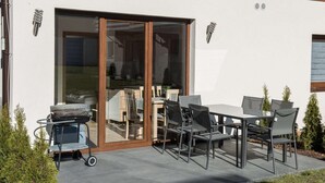 An outdoor patio with a grill, dining table, and chairs. - Spacious 3-room apartment, summer pool (Jaroslawiec)