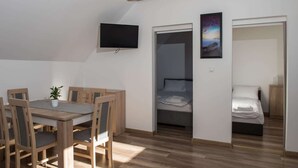 Una habitación compacta con una mesa de comedor y sillas, una cama, un televisor y un cuadro.