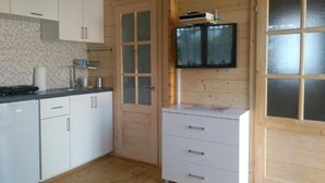 Una cocina con armarios blancos, un microondas y un televisor montado en la pared.