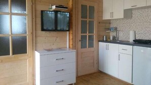 Una habitación con paneles de madera, televisor empotrado, armarios blancos y salpicadero de azulejos.