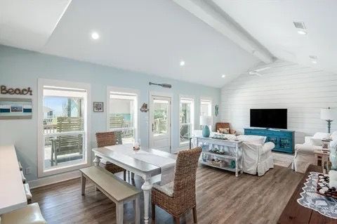 A spacious living area with a dining table, chairs, a sofa, and a TV.