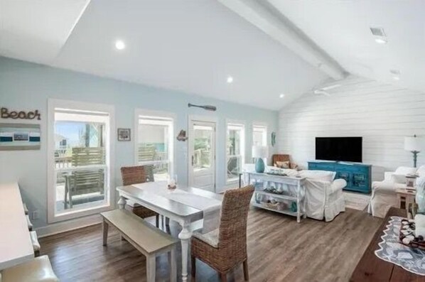 A spacious living area with a dining table, chairs, a sofa, and a TV.