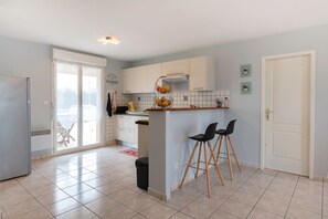 A modern kitchen with a central island, bar stools, and a sliding glass door leading to a balcony.