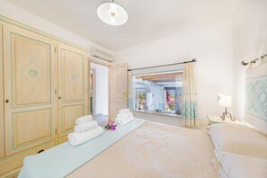 A hotel room with a large bed, a window with a view, and a wardrobe.