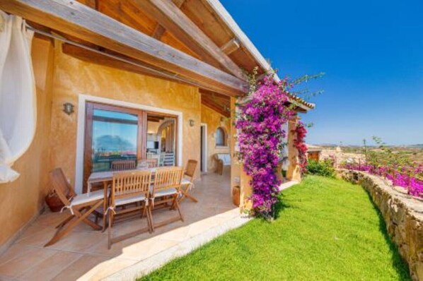 A wooden villa with a patio, a dining area, and a view of the countryside.