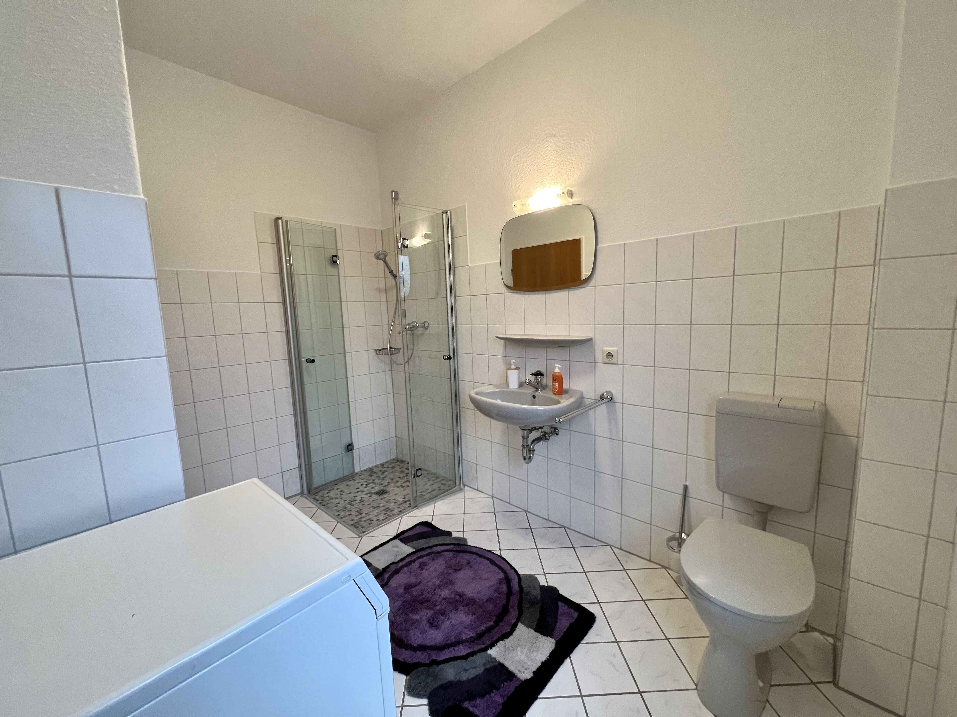 A bathroom with a glass-enclosed shower, a sink, and a toilet.
