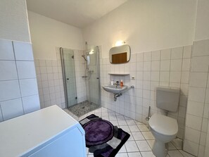 Kylpyhuone, jossa on lasiseinällä varustettu suihku, pesuallas ja wc.