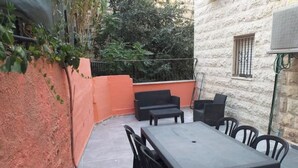 Une terrasse extérieure avec une table et des chaises, un canapé et un mur en pierre.