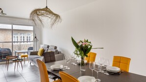 A modern dining area with a dark table set for six, surrounded by yellow chairs.