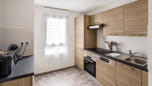 A modern kitchen with wooden cabinets, a black countertop, a built-in oven, and a stainless steel sink.