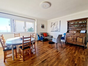 Un amplio salón con una mesa de comedor, sillas, un sofá y un armario.