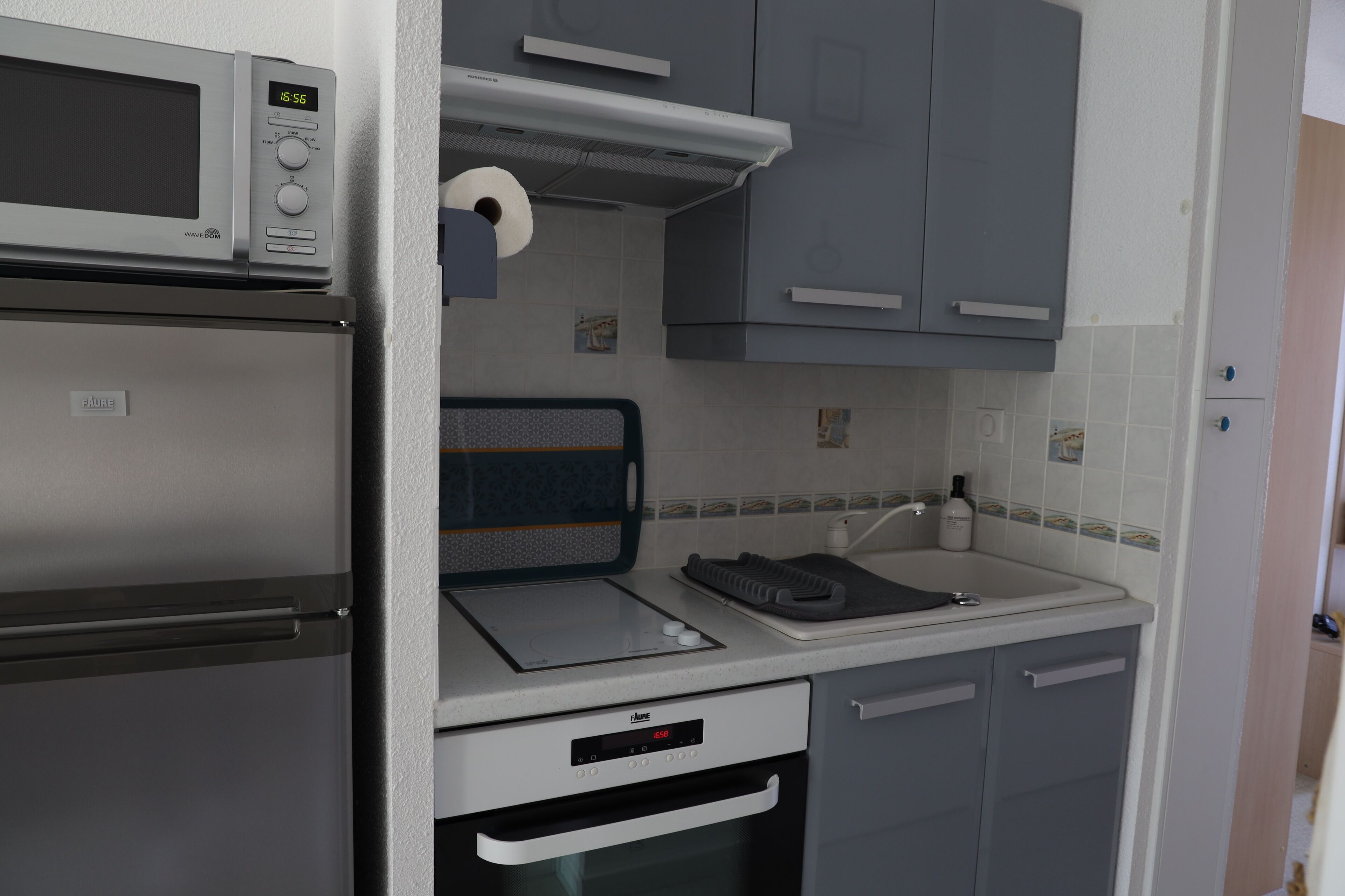 A compact kitchenette with a microwave, a small oven, a sink, and a toaster.