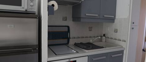 A compact kitchenette with a microwave, a small oven, a sink, and a toaster.