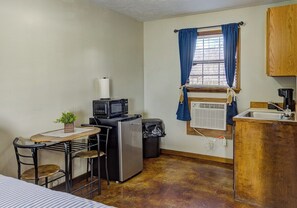 A compact kitchenette with a microwave, refrigerator, and sink. There is a small dining table with chairs and a potted plant. - Lakefront Hotel Room w/ Private Pier & Boat Ramp (Vicksburg)